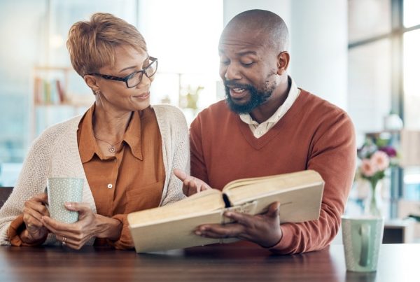 Man and wife sitting at table together, looking at book and making choices for funeral