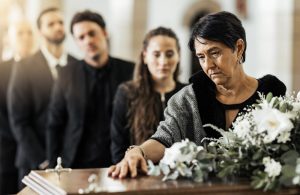 Woman standing at casket, giving final respects; line of people behind her waiting to give their own final respects