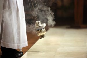 Priest spreading incense at a Catholic funeral