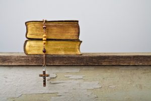 Catholic Bible sitting on desk with rosary laid on top