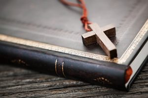 Wooden Christian cross necklace laying on book