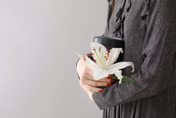 Woman in black dress holding black urn and white lily