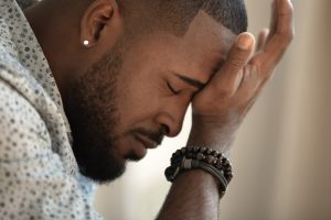 Focus on man's profile, placing his hand on his forehead