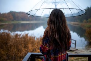 Woman under an umbrella, standing near a lake