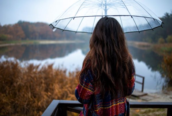 Woman under an umbrella, standing near a lake