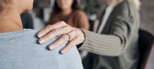 woman placing her hand on another person's shoulder