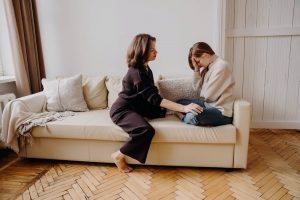 Mother and daughter sitting on couch, daughter sad and mom comforting