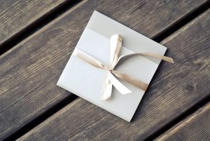White envelope with light beige ribbon laying on wooden table