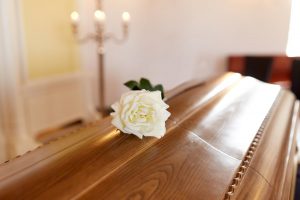 White rose on closed wooden casket