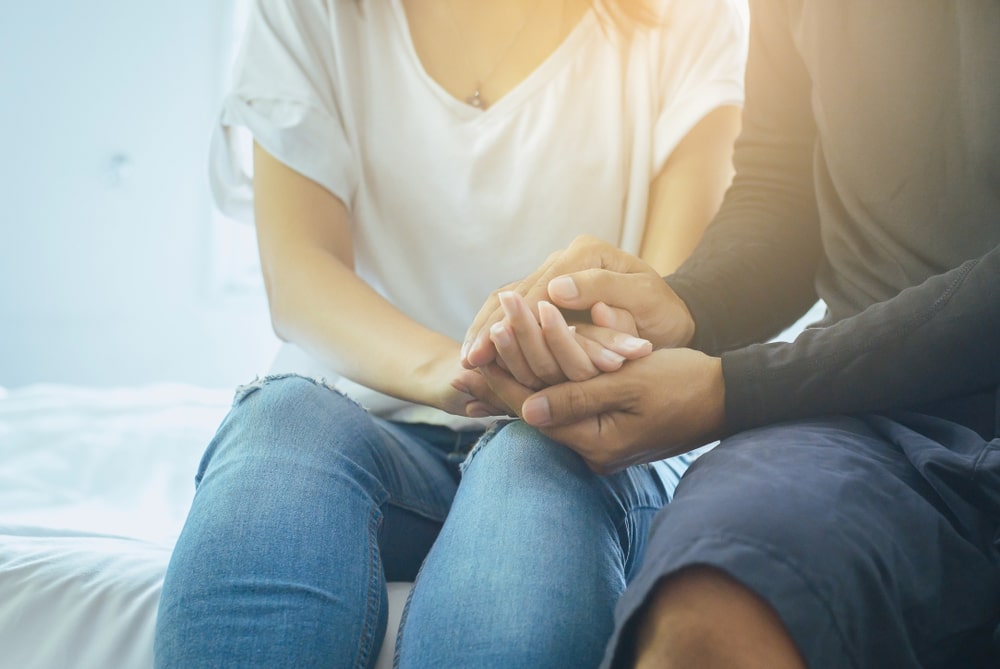 Two grieving people comforting each other