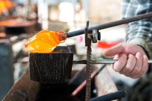 Glass blowing; man creating glass creation
