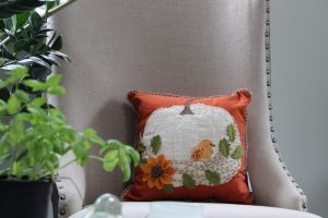 Embroidered pillow with orange bird on it