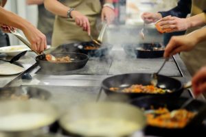 cooking class with people stirring food in skillets