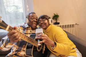 elderly couple singing and playing guitar together