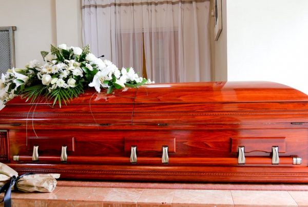 Wooden casket with spray of white flowers on top