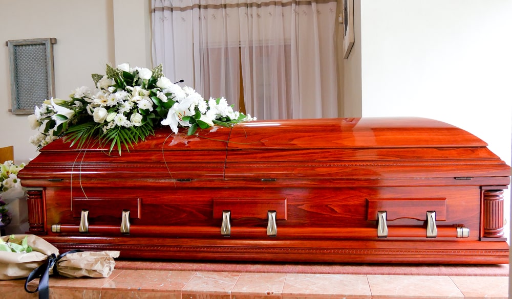 Wooden casket with spray of white flowers on top