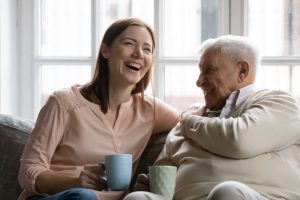 woman and her elderly father drinking coffee and laughing together