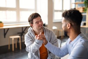 young man encouraging a boy with Down syndrome