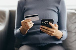 Woman holding a credit card while sitting on her couch