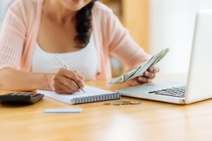 Woman in pink cardigan sitting at table at home making a budget