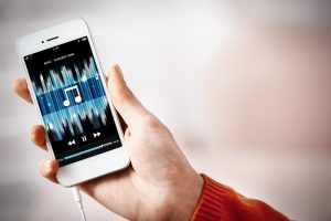 Person holding a smartphone that displays a digital music playlist