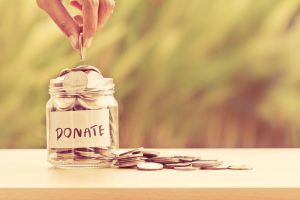 Person placing money in a jar labeled "donate"