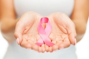 Two hands holding a pink breast cancer awareness ribbon