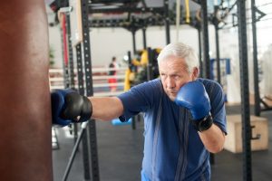 older man hitting a punching bag at a gym as a workout