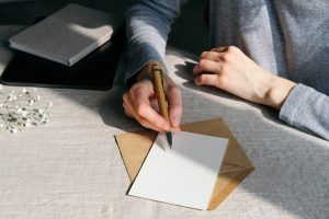 woman wearing a gray shirt writing in a card