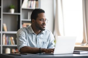 Young man sitting at home, watching a livestream on his computer