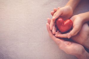 parent and child hands holding a heart