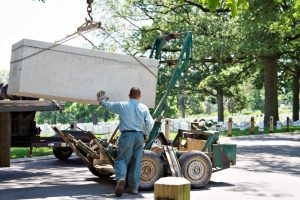 Cemetery worker overseeing arrival of an outer burial container