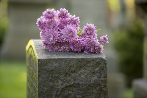 Bouquet of purple flowers resting on top of a headstone or grave marker