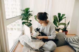 Woman at home working on computer with cat sitting in her lap