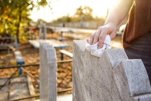 person wiping a headstone with a white cloth