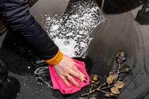 woman's hand using a cloth to wipe cleaning products on a headstone