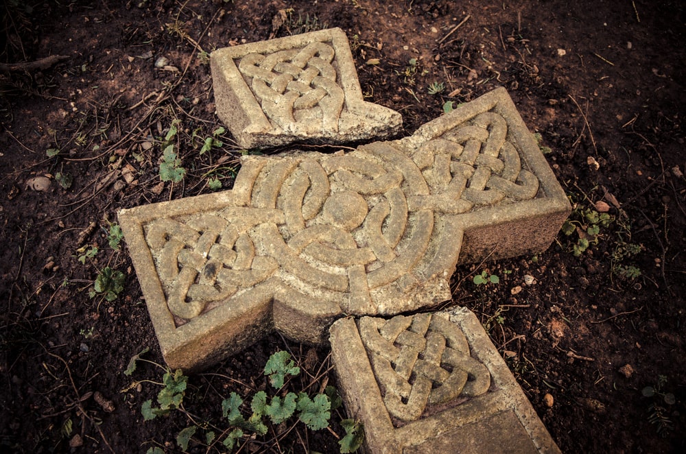 Cross-shaped headstone fallen over and broken in several places