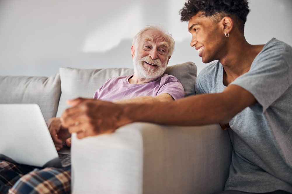 young african american man talking to an elderly caucasian man who is sitting on a couch