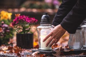 Person leaving a remembrance candle at a loved one's final resting place
