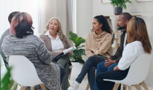 Group of six people sitting in a circle as part of a grief support group