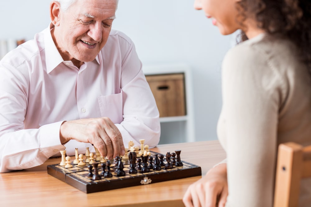 young female volunteer playing chess with an older man