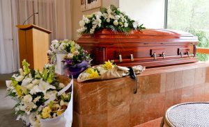Closed wooden casket with flowers and a podium nearby