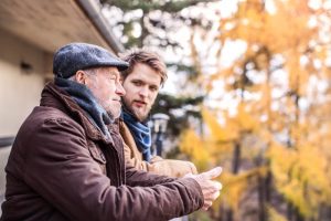 Mature man and adult son standing outside and talking