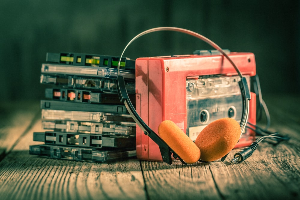 Orange walkman with pile of cassette tapes beside it
