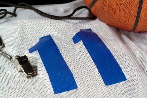 Basketball jersey with number 11 in blue next to a whistle and basketball