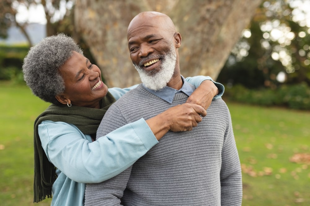 elderly african american couple smiling and hugging outside
