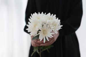 Woman wearing black holding white chrysanthemums