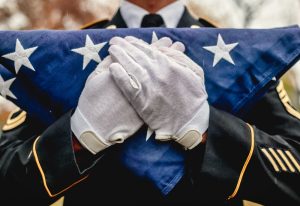 Military service member holding a folded American flag