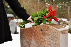 Person visiting a loved one's final resting place and leaving red roses as a token of their love