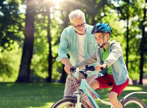 older man helping a young boy ride a bike